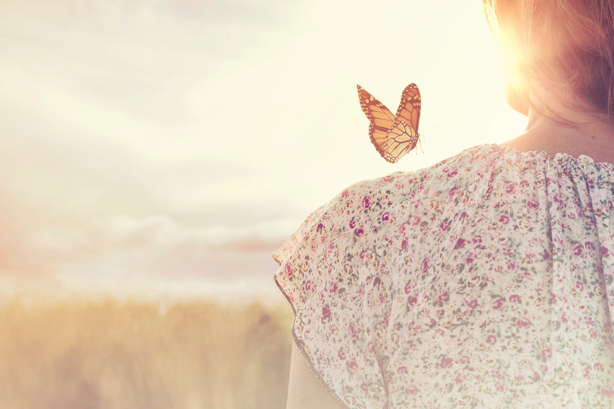 Schmetterling sitzt auf Schulter einer Frau