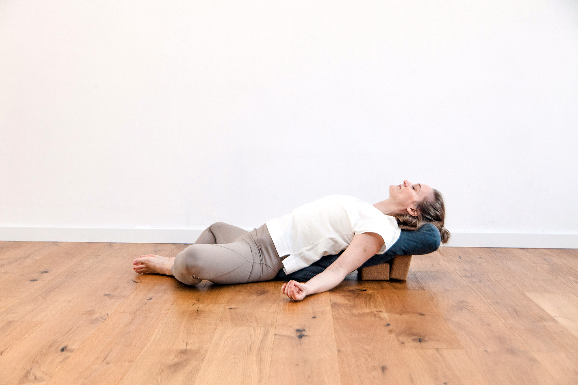 Frau liegt auf einem großen Kissen auf dem Boden und macht Yoga