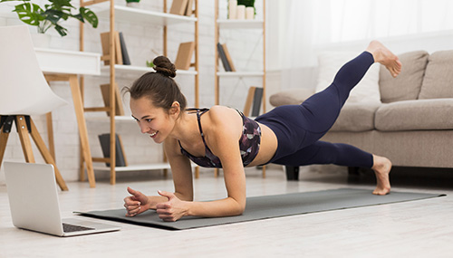 Frau macht Yoga am Boden mit Laptop