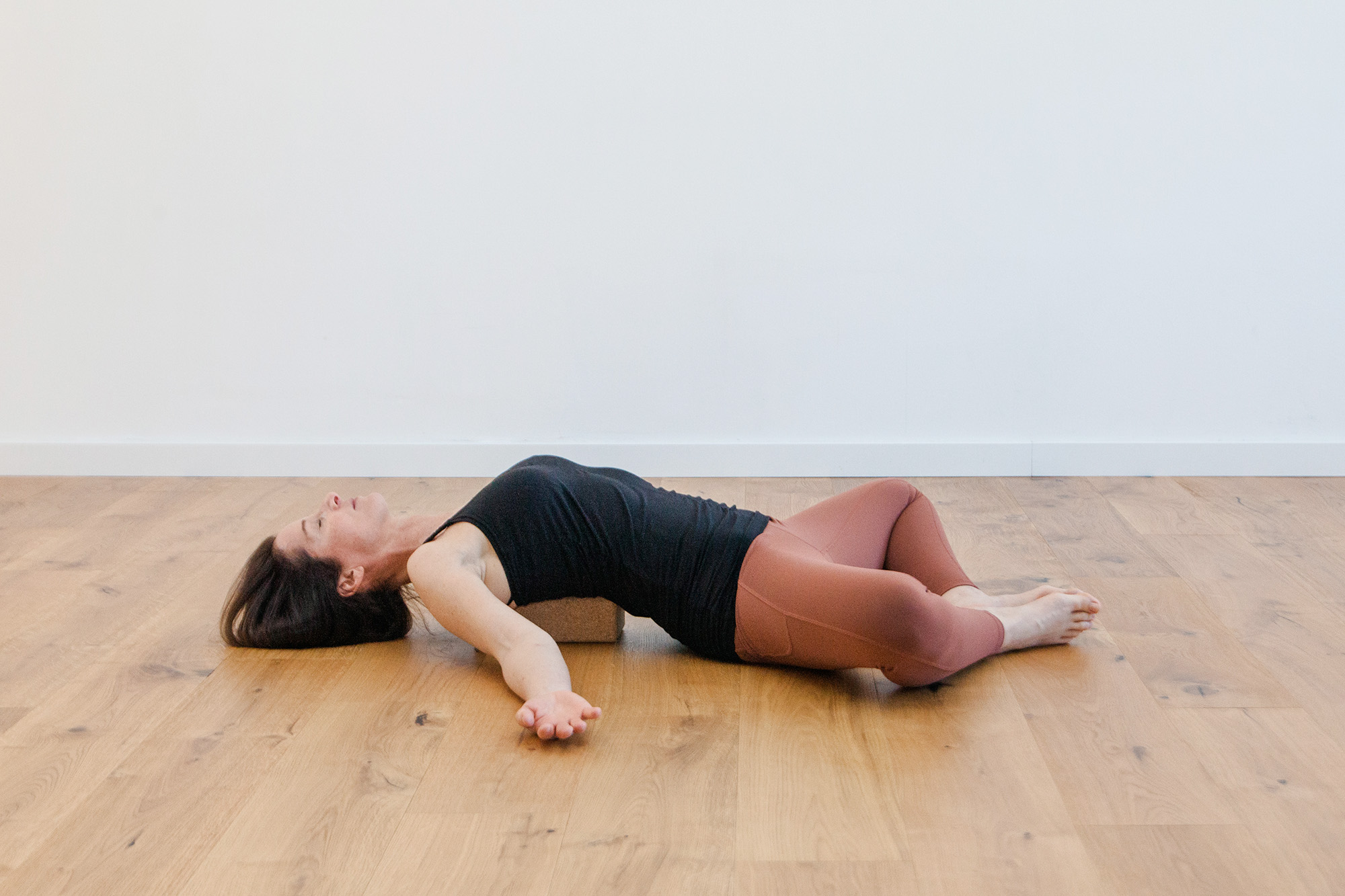 Frau liegt am Boden in einer Yogaposition